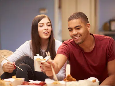 Couple enjoying a casual date night with takeout food, emphasizing soft food choices suitable for individuals with braces.